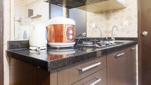 Una cocina con estufa, cafetera y cocedor de arroz sobre la encimera.