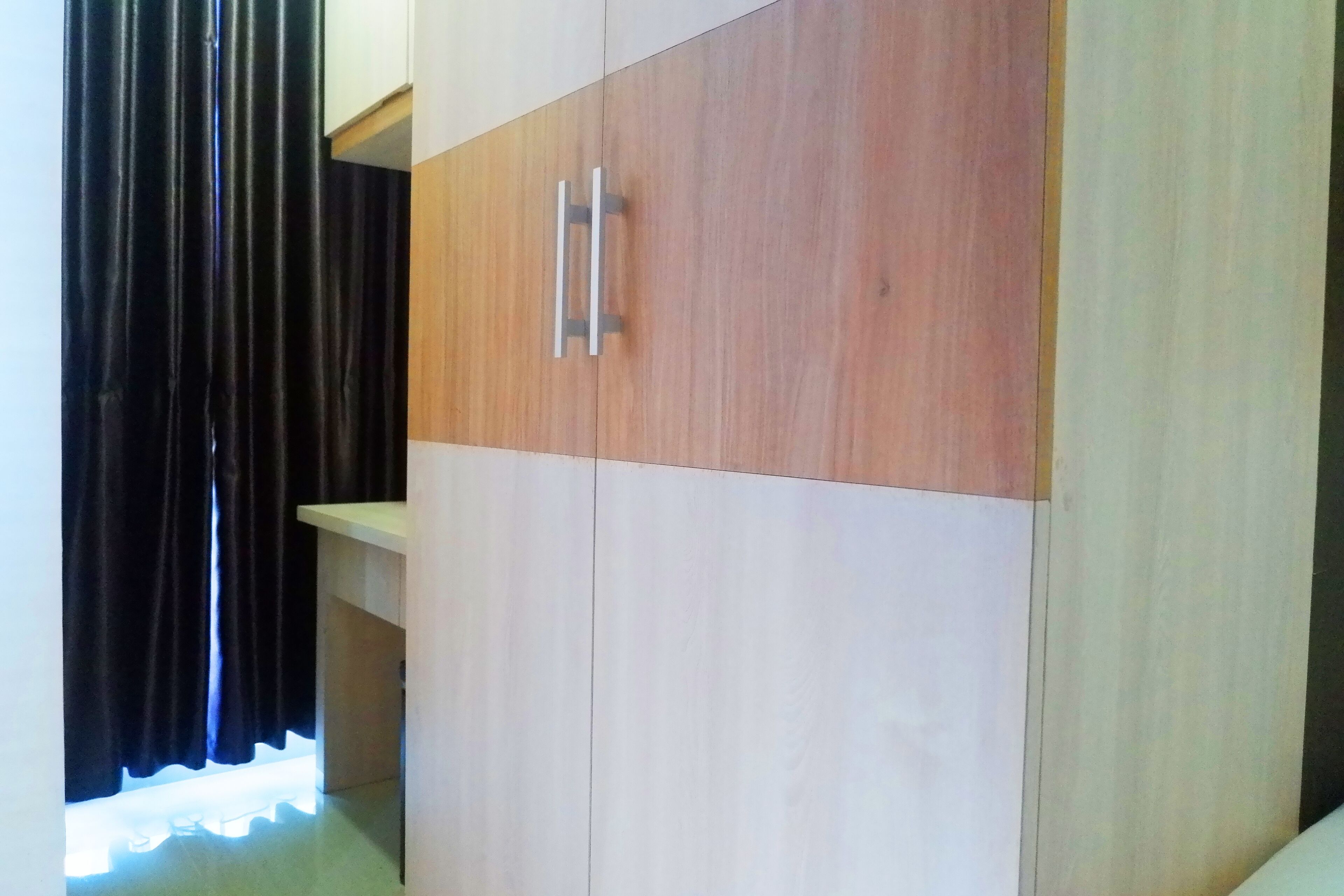 A wardrobe with a light wood finish and a metal handle.