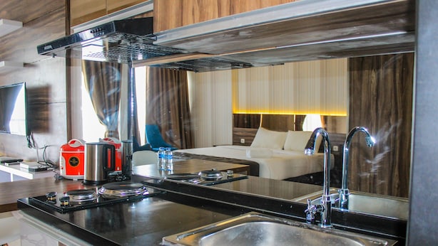 A modern kitchen with a stainless steel sink, a coffee maker, and a microwave. - Minimalist and Stylish Studio Parkland Avenue Apartment (South Tangerang)