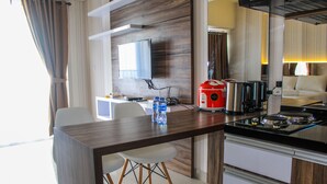 A modern kitchen with a dining area, a flat-screen TV, and a coffee maker. - Minimalist and Stylish Studio Parkland Avenue Apartment (South Tangerang)