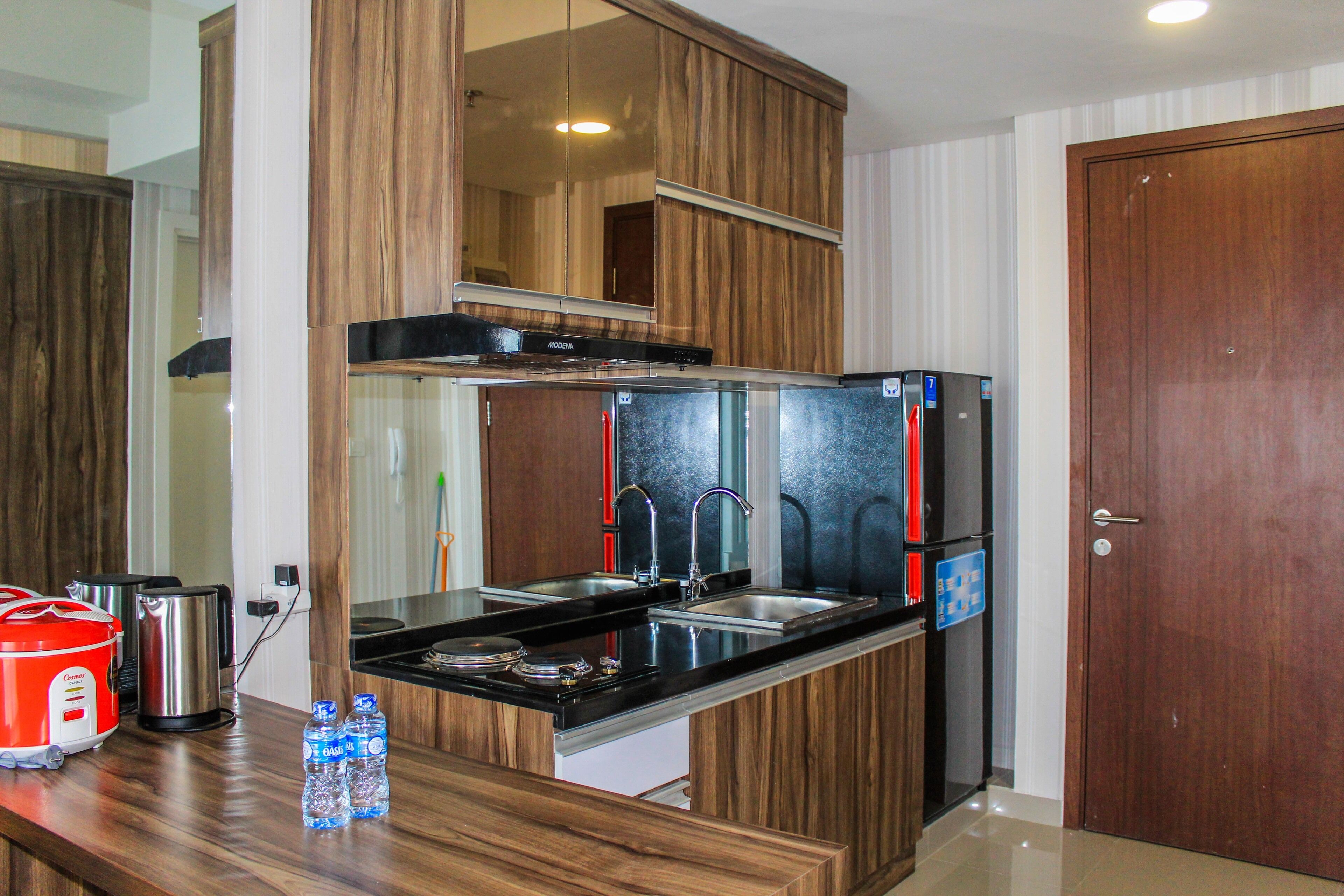 A compact kitchen with wooden cabinets, stainless steel appliances, and a black countertop.