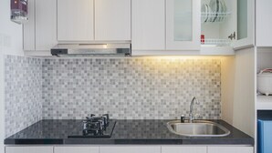 Une cuisine moderne dotée d’un plan de travail noir, d’un évier en acier inoxydable et d’une cuisinière à gaz.