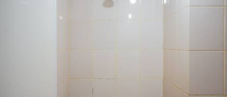 A bathroom with white tiled walls and a showerhead.