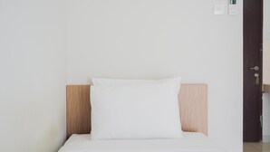 A single bed with a wooden headboard and white bedding in a hotel room. - Chic Studio at Serpong Green View Apartment (South Tangerang)