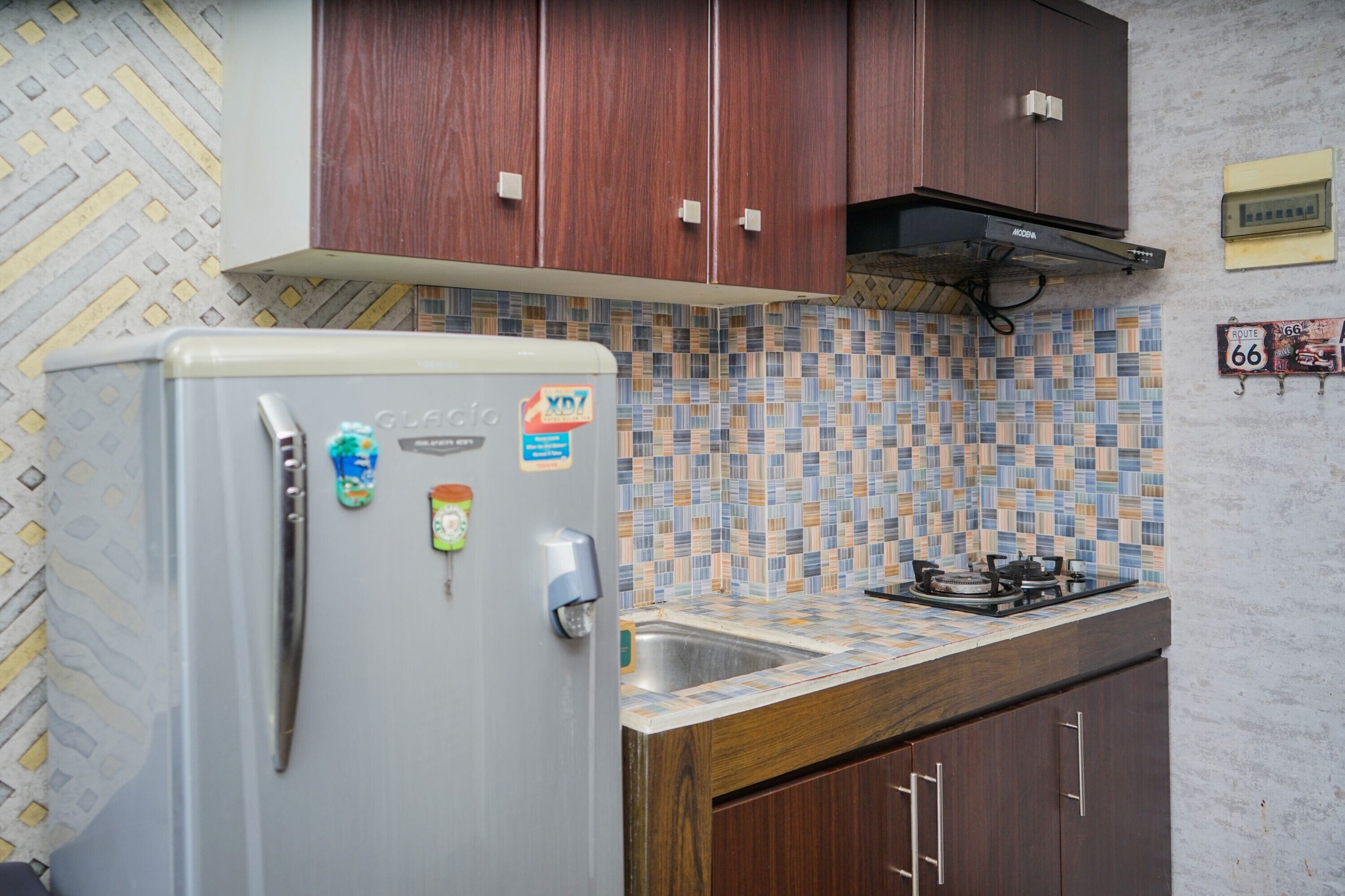 A kitchen with a refrigerator, a gas stove, wooden cabinets, and a tiled backsplash.