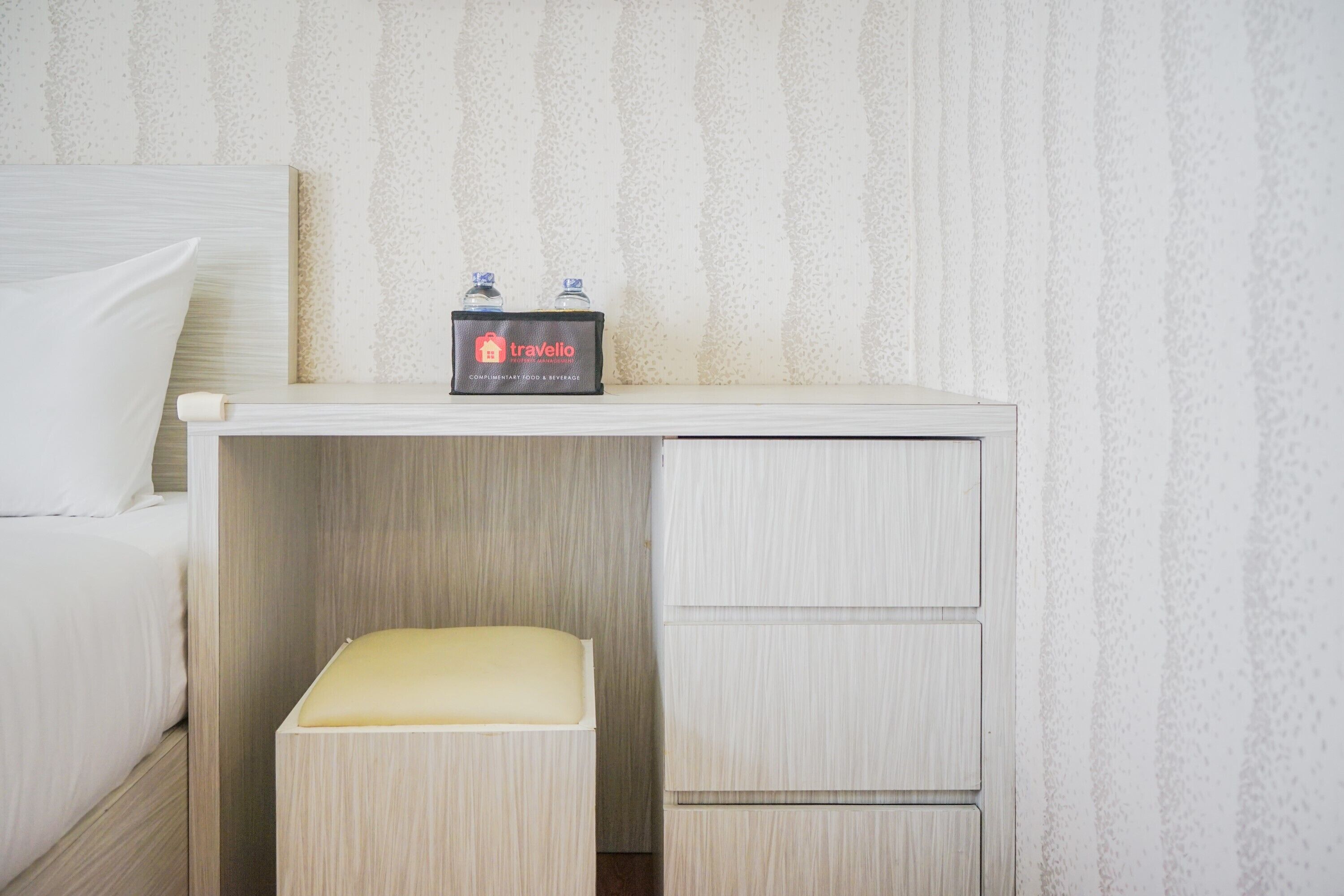 A hotel room with a bed, a small desk with a tray table, and a minibar.