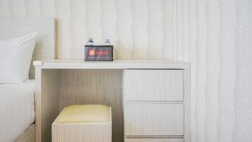 A hotel room with a bed, a small desk with a tray table, and a minibar.