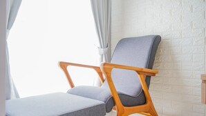 Une chaise et une table dans une pièce aux murs en briques blanches et dotée d’une fenêtre ornée de rideaux blancs.