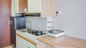 Une cuisine de taille réduite, équipée d’un évier, d’une cuisinière et d’un petit plan de travail.