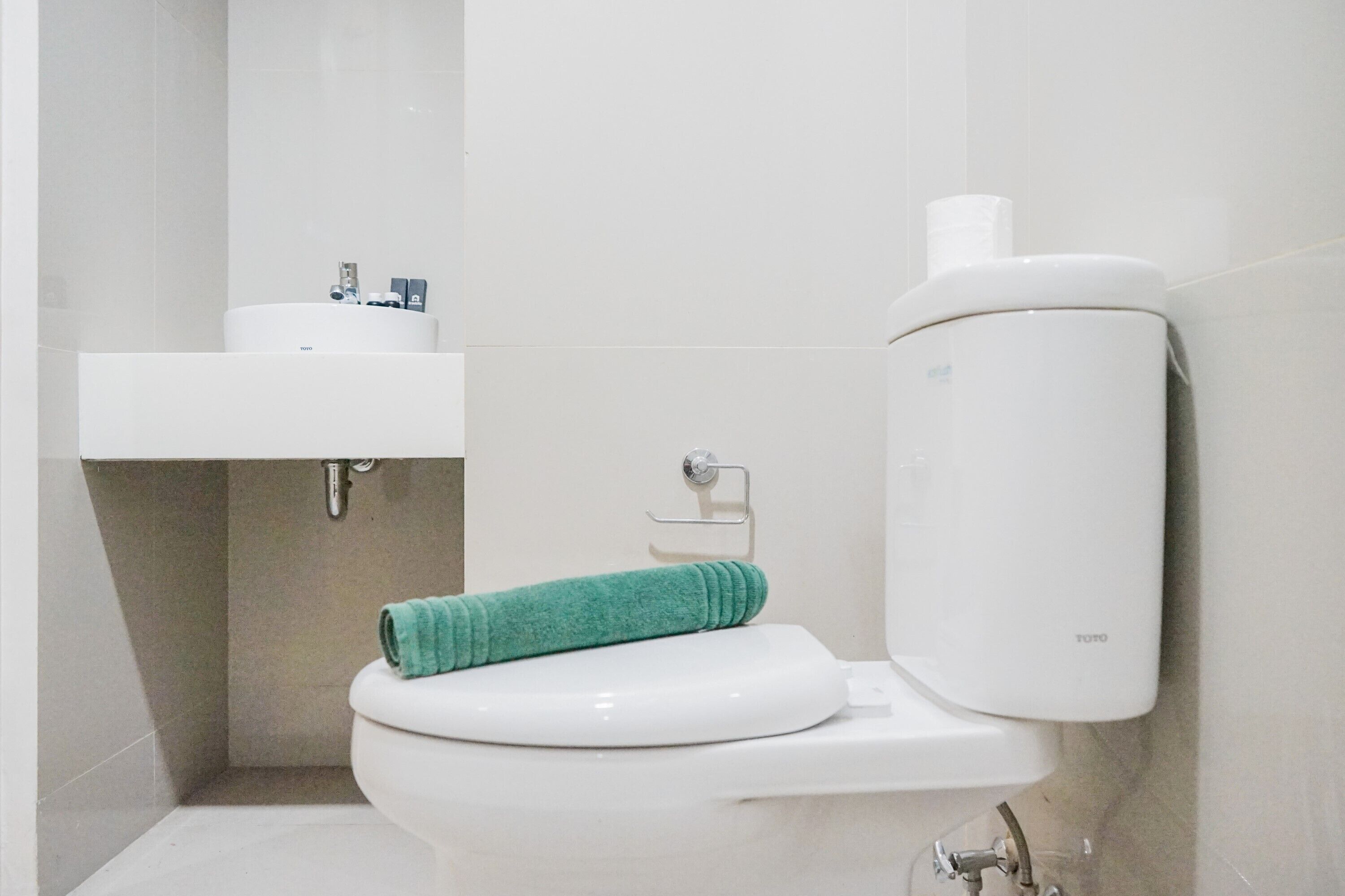 Une salle de bain moderne équipée de toilettes, d’un lavabo et d’un porte-rouleau de papier toilette.