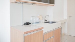 A modern kitchen with white cabinetry, a stainless steel sink, and a built-in dishwasher. - Wonderful Studio Apartment at Tree Park (South Tangerang)