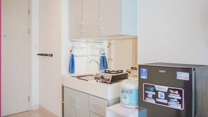 A compact kitchen with a refrigerator, a sink, and cabinets. - Cozy and Relax Studio Room @ Tree Park BSD Apartment (South Tangerang)