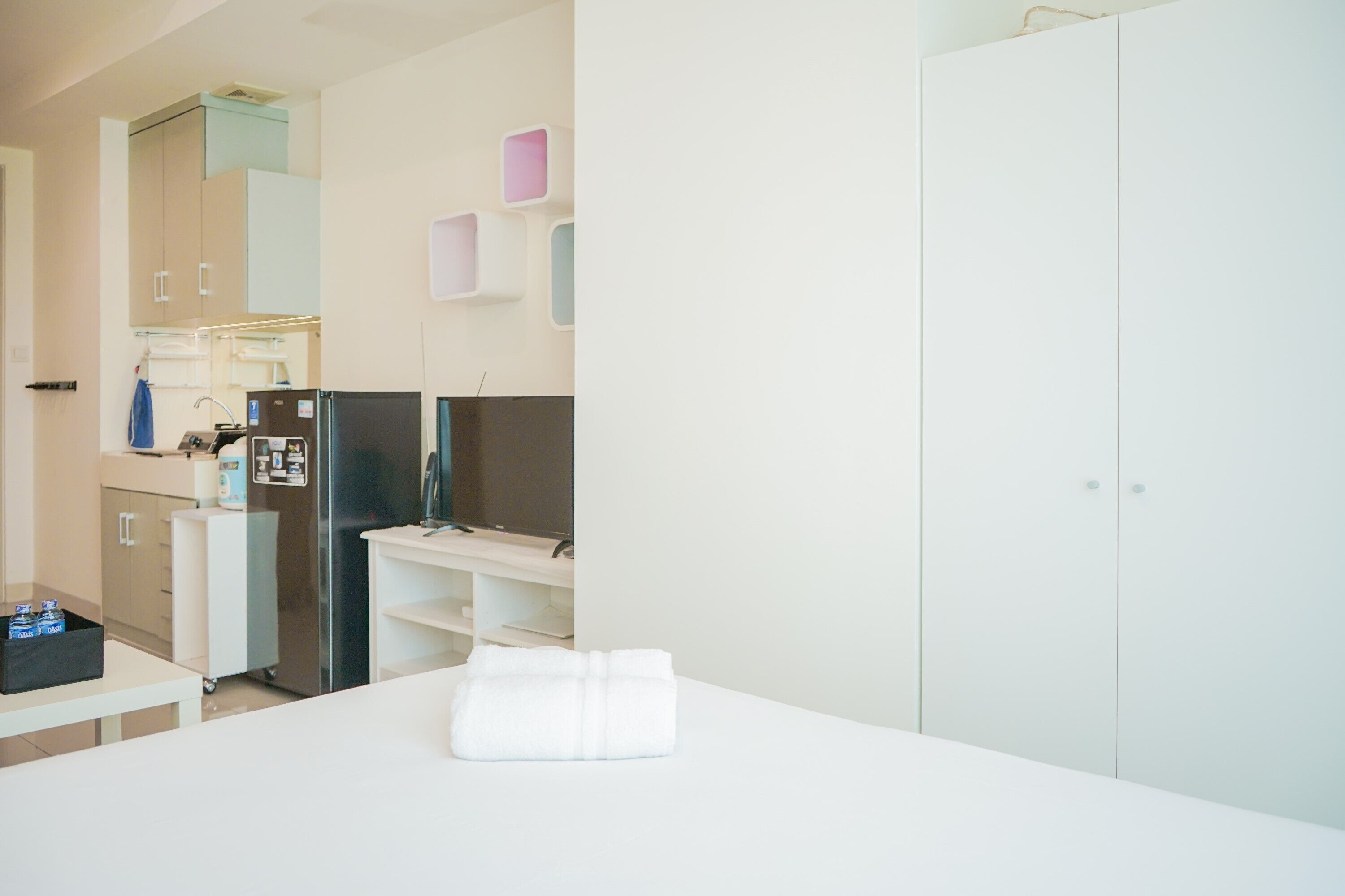 Una camera d'albergo moderna con un letto, una scrivania, un frigorifero e una televisione.