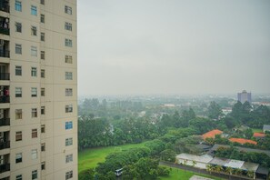 Un edificio de gran altura con varios pisos y balcones, con vistas a una zona verde con árboles y algunos edificios a lo lejos.