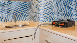 A kitchen with blue and white mosaic tiles, a stainless steel sink, and a portable gas stove. - Compact and Mini Studio Great Western Resort Apartment (Tangerang)