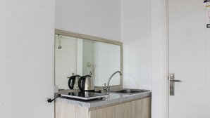 A compact kitchen with a countertop, a kettle, and a sink. - Minimalist Studio Apartment at Poris 88 with City View (Tangerang)