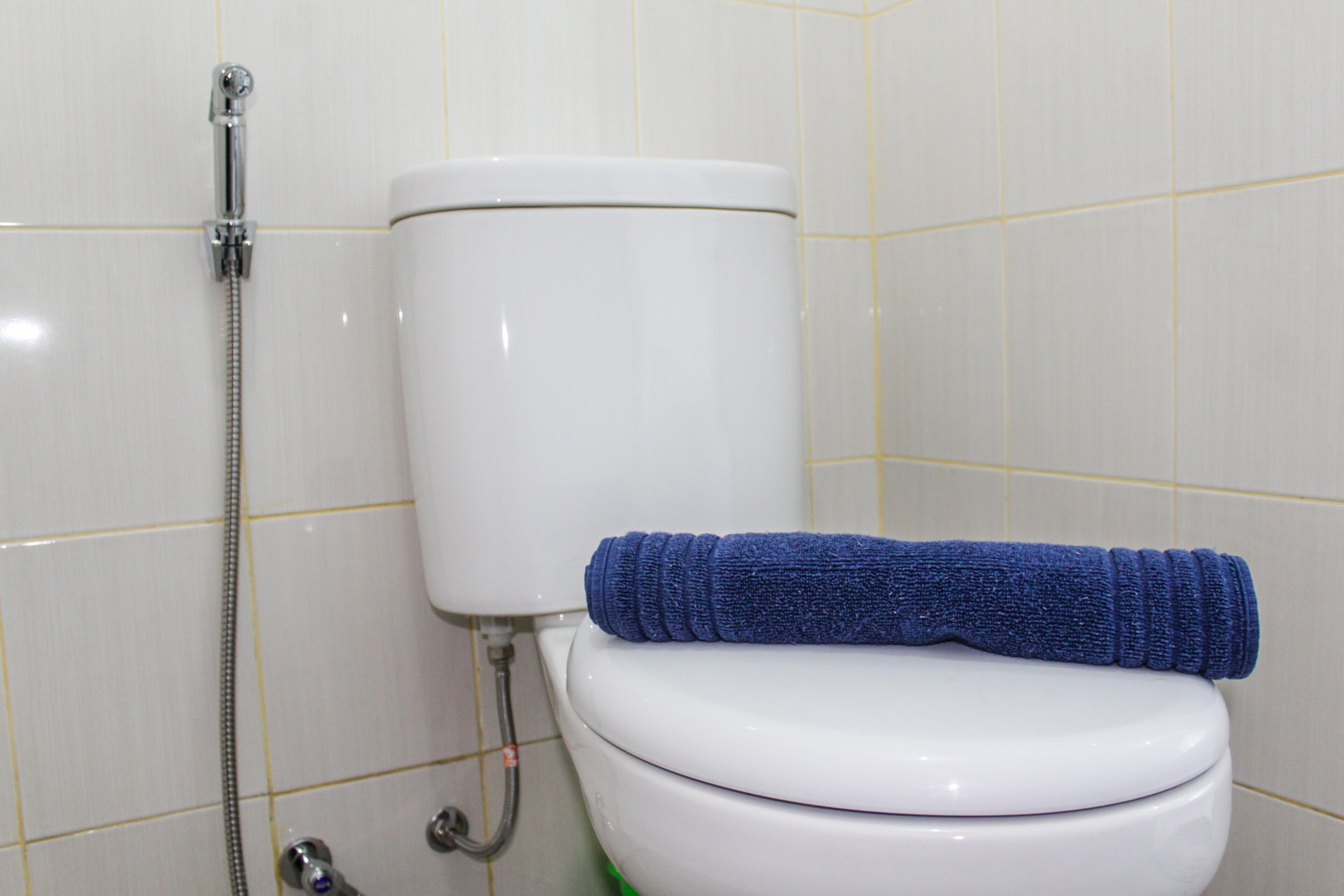 Een toilet met een blauwe handdoek en een douchekop aan de linkerkant.