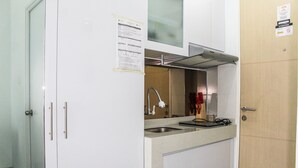Eine kleine Küche mit Spüle, Herd und Mikrowelle. Es gibt Schränke und eine Tür mit Griff.