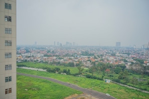 A high-rise building overlooking a cityscape with a road and greenery. - New Furnished 2BR near CGK Airport @ Ayodhya Apartment (Tangerang)