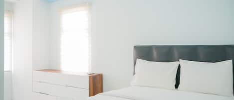 A neatly arranged bedroom with a bed, a bedside table, and a window.