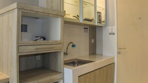 Una cucina compatta con lavello, mobili in legno e un pensile con ante in vetro.