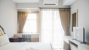 Une chambre d’hôtel avec un lit, un bureau, une chaise, une télévision et des rideaux.