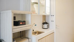 Une cuisine compacte équipée d’un four encastré, d’un évier et d’un réfrigérateur de petite taille, idéal pour les voyages.