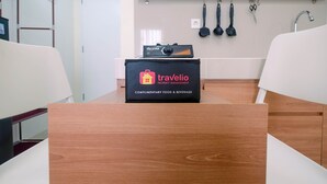 A wooden table with a black box labeled 'travelio' and kitchen utensils on the wall.