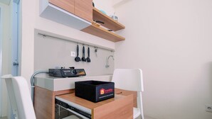 A compact kitchenette with a wooden countertop, a black box labeled "travelio," and a dish rack.