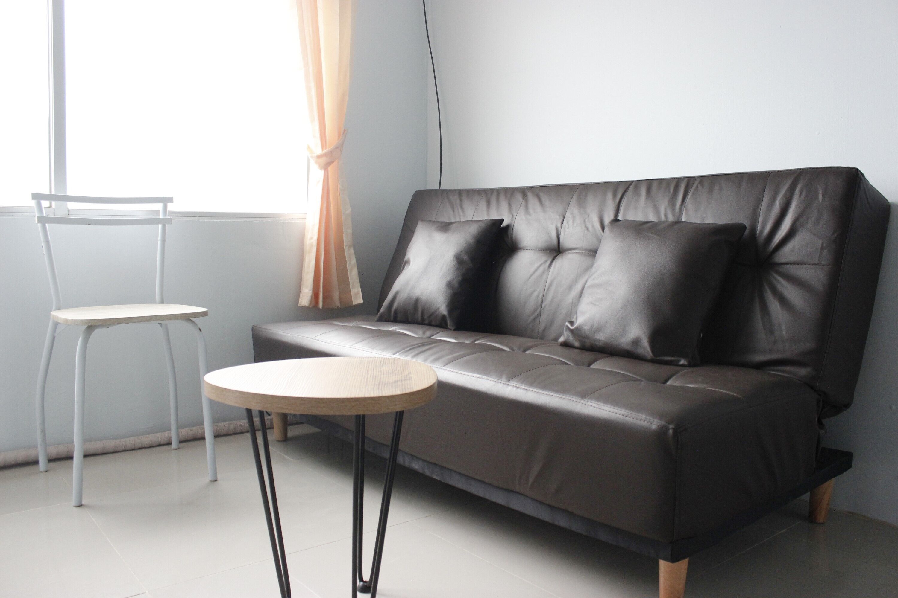 A modern living room with a leather sofa, a small round table, and a chair.