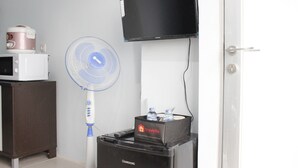 A room with a microwave, a fan, a television, and a minibar. - Quite 2BR Apartment at The Jarrdin Cihampelas (Bandung)
