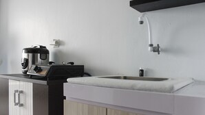 A kitchen with a coffee maker, a sink, and a faucet. - Modest 2BR Apartment at The Jarrdin Cihampelas (Bandung)