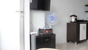 A compact kitchenette with a microwave, a small refrigerator, a travelio coffee machine, a flat-screen TV, and a wall-mounted fan. - Modest 2BR Apartment at The Jarrdin Cihampelas (Bandung)