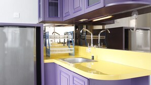 A modern kitchen with purple cabinets, a stainless steel refrigerator, and a yellow countertop. - Spacious & Trendy Studio at Jarrdin Cihampelas Apartment (Bandung)