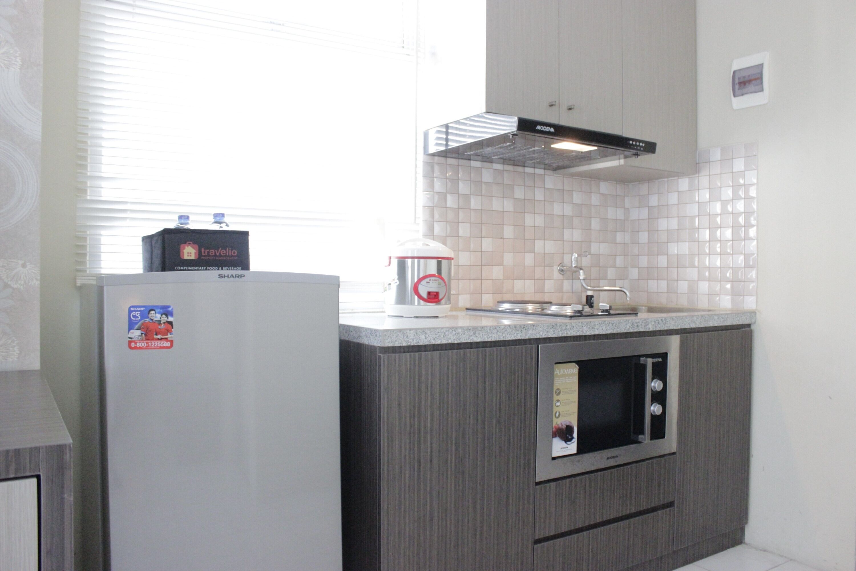 A compact kitchen with a refrigerator, a microwave, and a water dispenser.