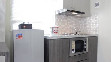 A compact kitchen with a refrigerator, a microwave, and a water dispenser.