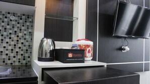Una cocina moderna con cafetera, una caja con la etiqueta 'Travelio' y un televisor montado en la pared.