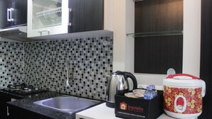 Cocina moderna con encimera negra, pileta, estufa y microondas. Hay una caja con la etiqueta 'Travelio' y una cocedora de arroz roja y blanca sobre la encimera.
