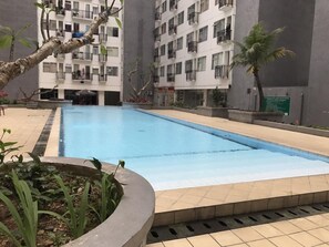 Relax by the rectangular pool surrounded by a tiled deck and lush greenery.