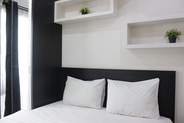 Relax in a serene space with a large bed and two potted plants.