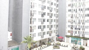 A multi-story residential building with balconies, a courtyard with seating, and a mural on the exterior wall.