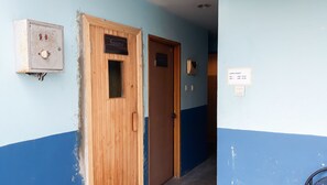 A hallway with a wooden door labeled "Sauna," a wall-mounted electrical box, and a sign indicating the lamp's operational hours. - Cozy and Minimalist 2BR at Marbella Kemang Apartment (Jakarta)