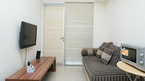 Una sala pequeña con un sofá, un televisor, una mesa de madera y una puerta corrediza.