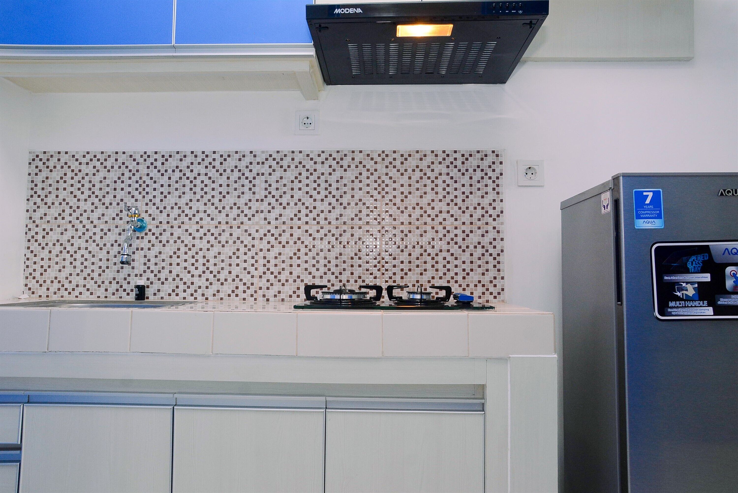 A kitchen with a tiled backsplash, a gas stove, and a refrigerator.