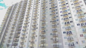 Un edificio residencial de gran altura con varios balcones, cada uno con un ventanal pequeño y barandilla metálica.