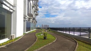 Un sendero que lleva a un edificio con varios balcones, vista al mar y cielo despejado.