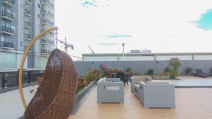 Terraza en la azotea con una silla colgante, mobiliario exterior y vistas de un edificio en construcción.