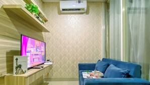 Una sala de estar con televisor, sofá y una pequeña mesa con una estatua.