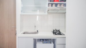 A modern kitchen with white cabinetry, a stainless steel sink, and a gas stove. - Comfy and Stylish 2BR Emerald Bintaro Apartment (South Tangerang)