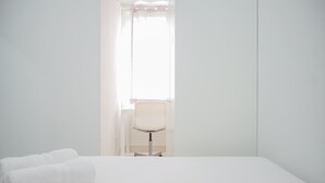 A white room with a bed, a chair, and a window with sheer curtains. - Comfy and Stylish 2BR Emerald Bintaro Apartment (South Tangerang)